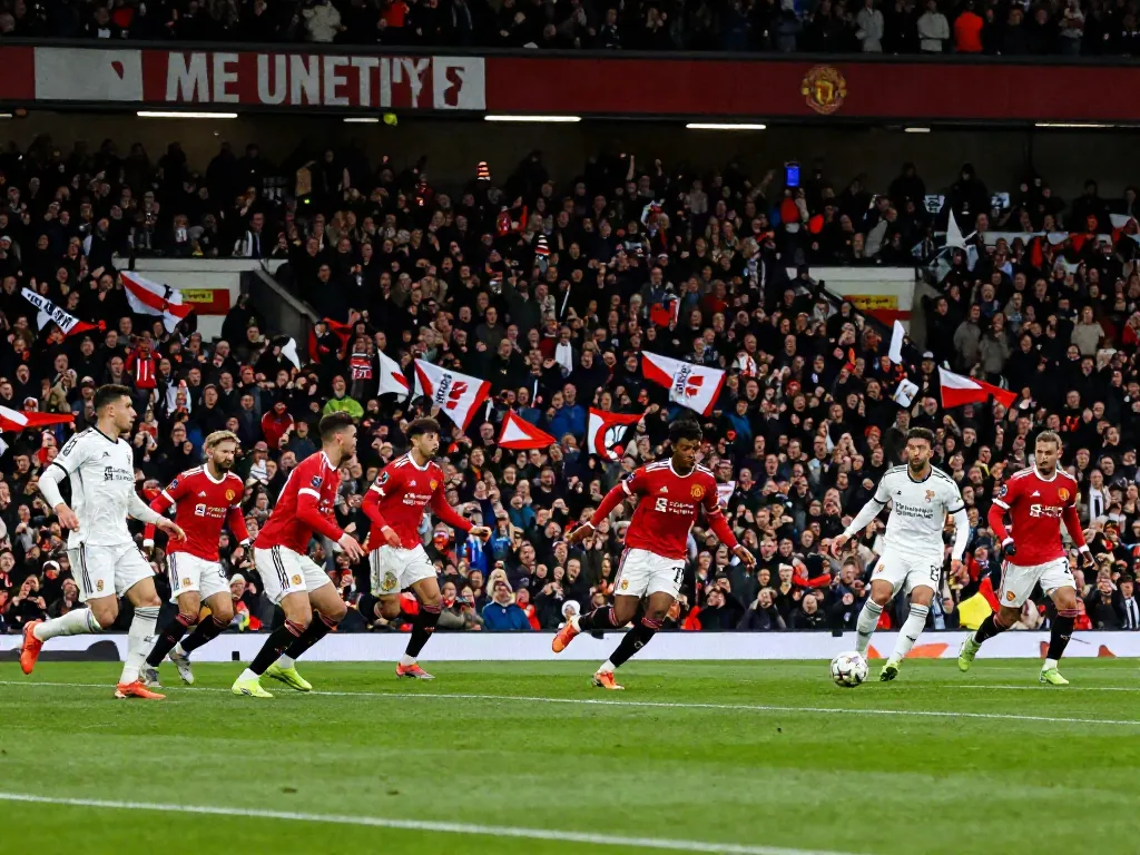 Intense แมนยู vs ลิเวอร์พูล soccer match showcasing players in action and cheering fans.